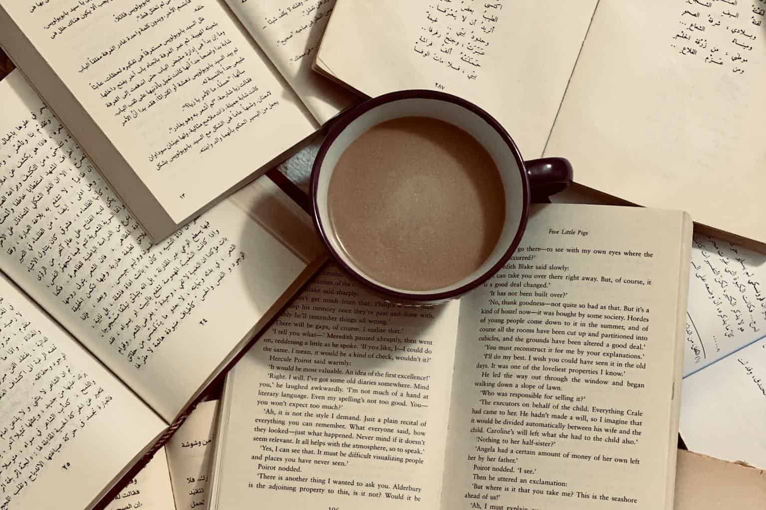 A collection of open books surrounding a coffee cup, providing a cozy reading vibe.