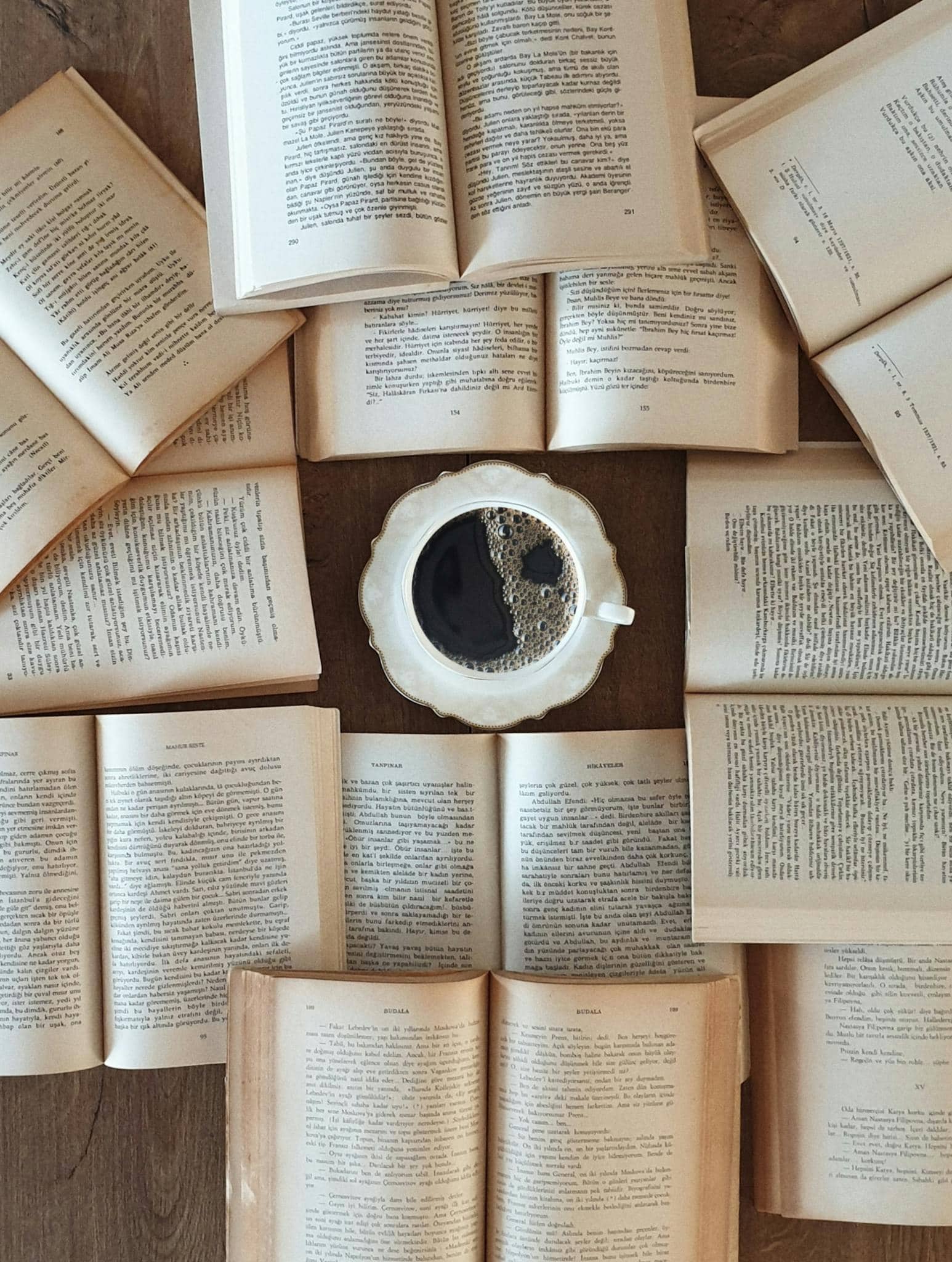 Flat lay of open books surrounding a coffee cup, perfect for a relaxing reading atmosphere.
